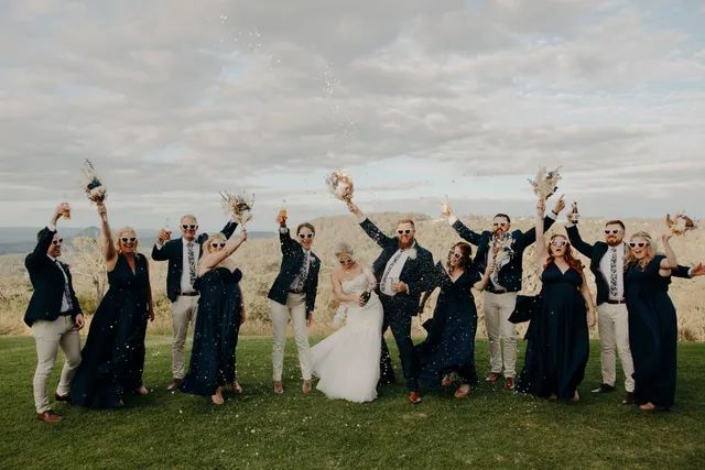 A bride and groom are posing for a picture with their wedding party.