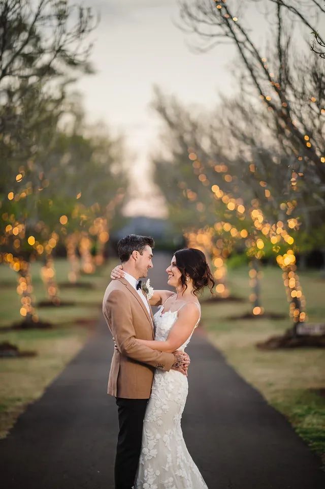 A bride and groom are standing next to each other on a path.