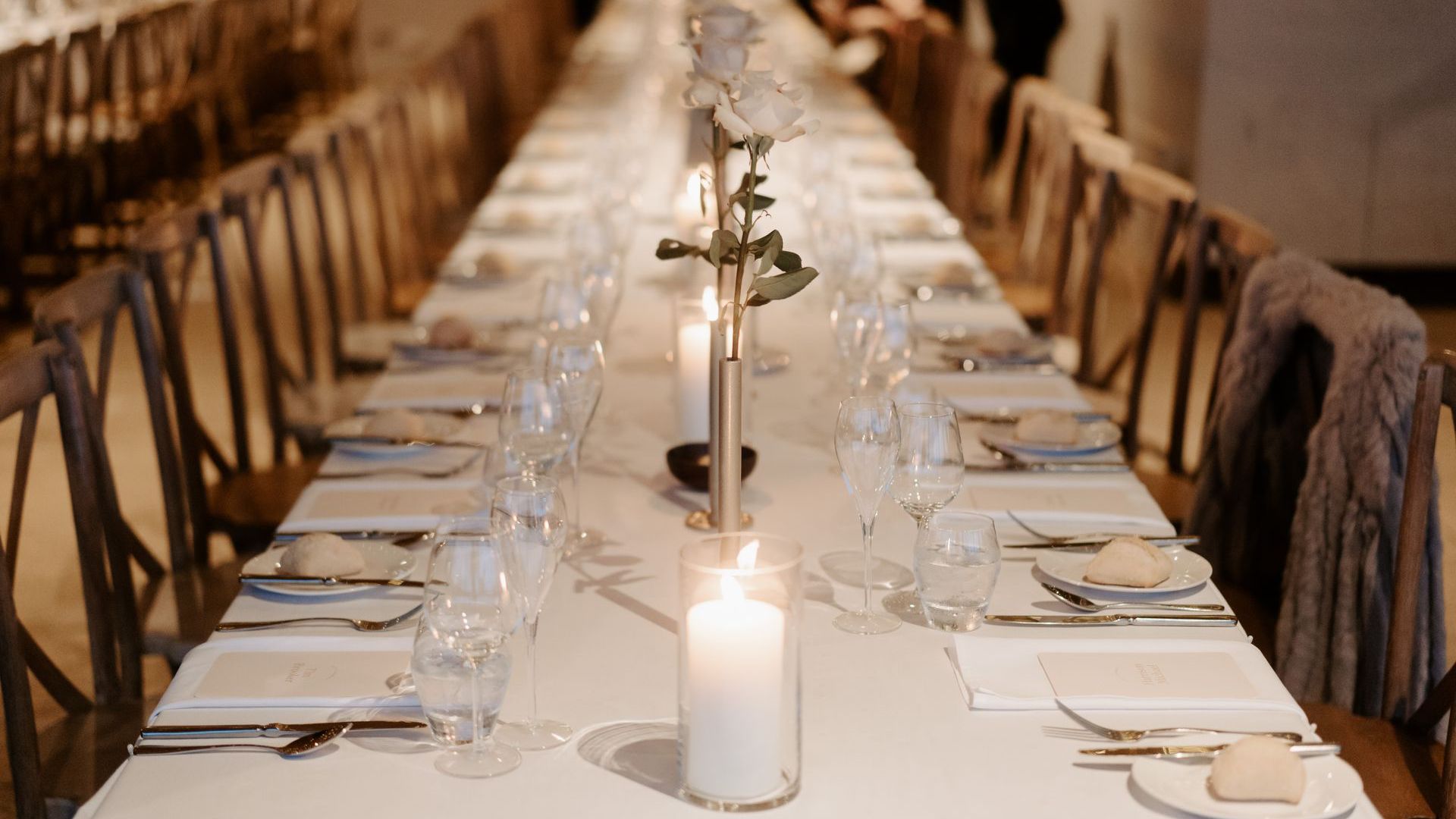 A long table set for a wedding reception with a candle in the middle.