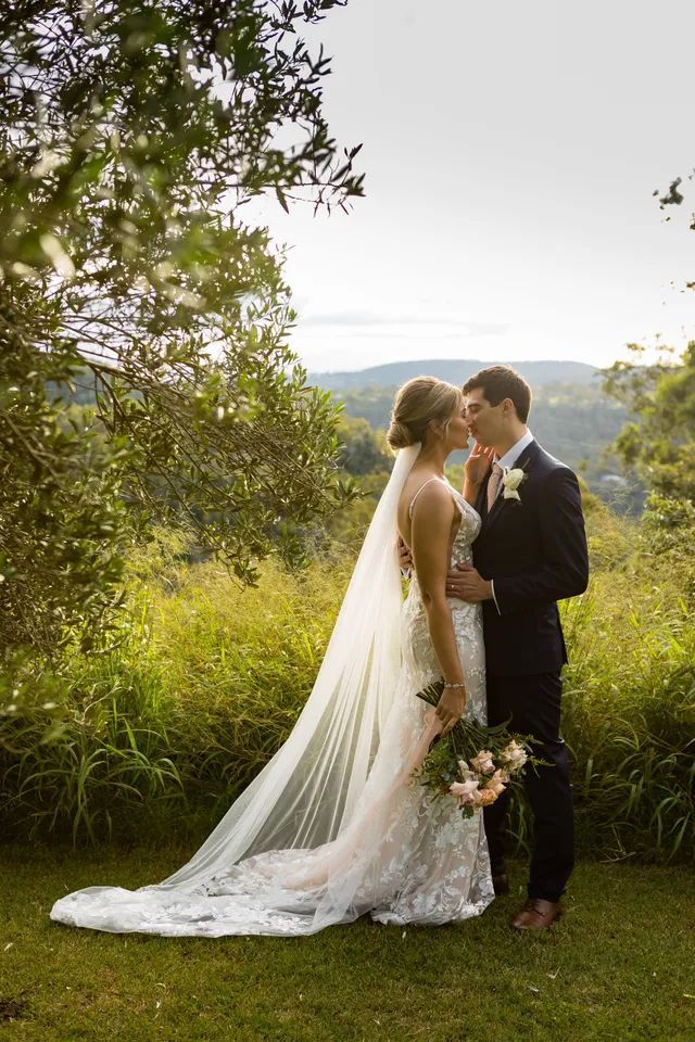 A bride and groom are posing for a picture in the grass.