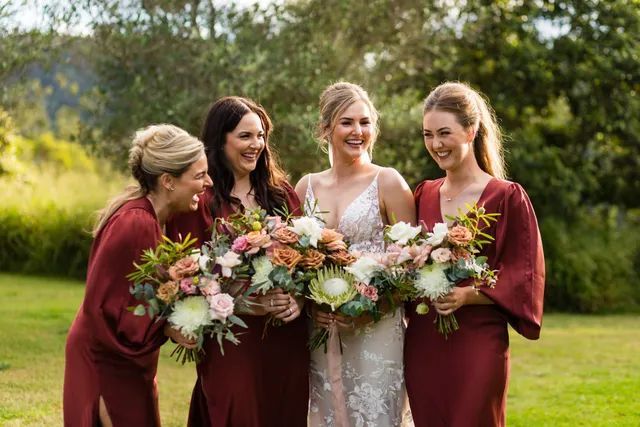 A bride and her bridesmaids are posing for a picture while holding bouquets of flowers.