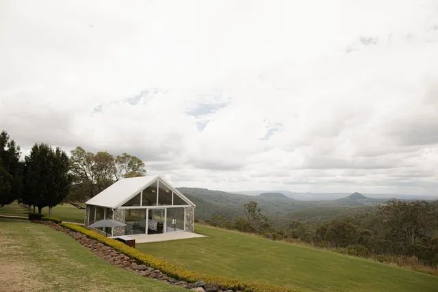 A small white house is sitting on top of a lush green hillside.