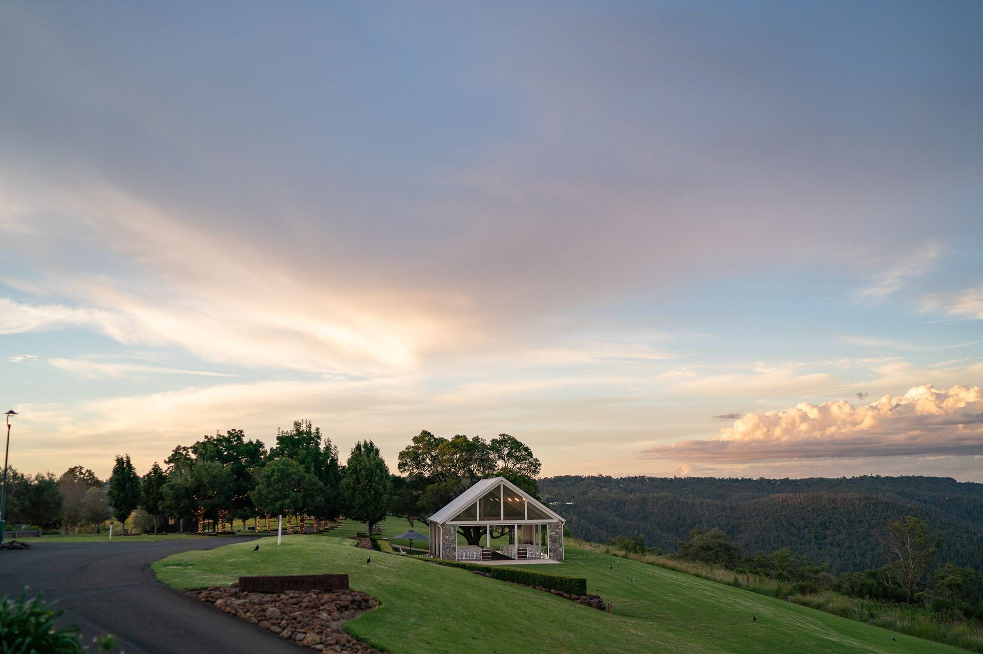 A small house is sitting on top of a lush green hillside.