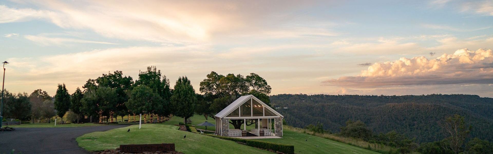 A small white house is sitting on top of a grassy hill.