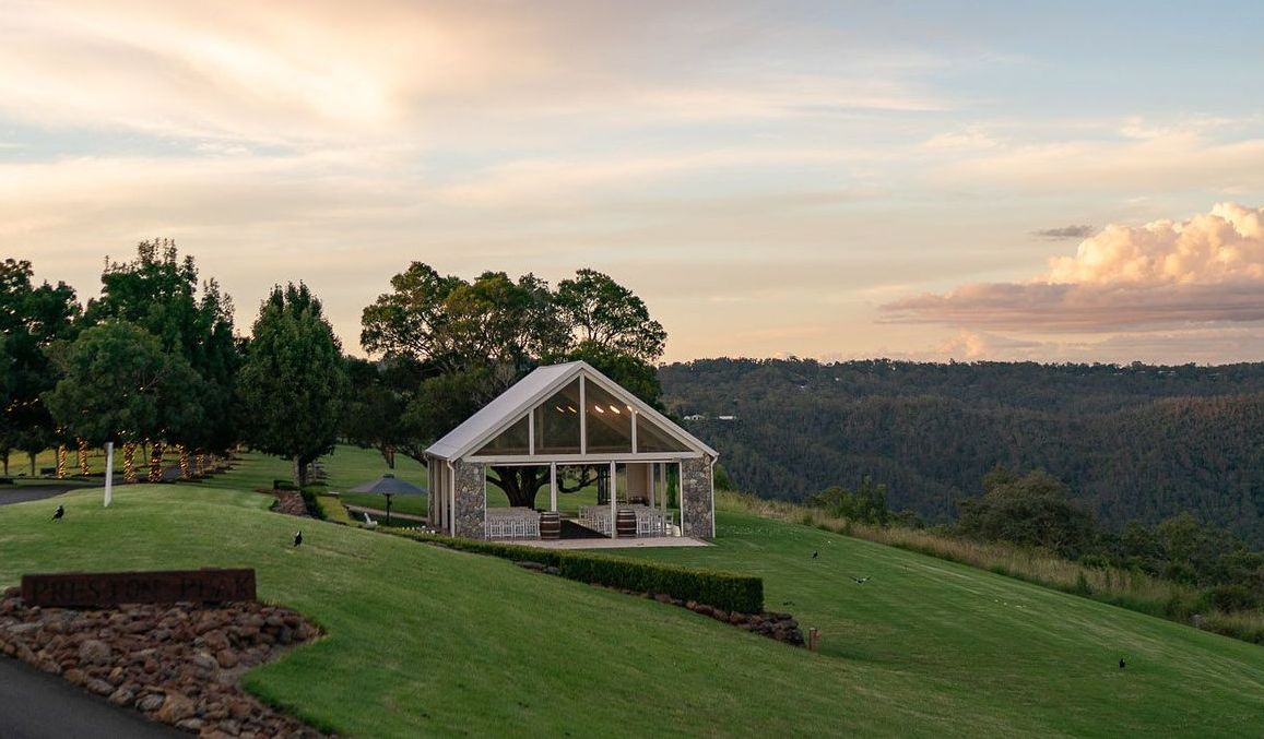 A large white tent is sitting on top of a lush green hillside.