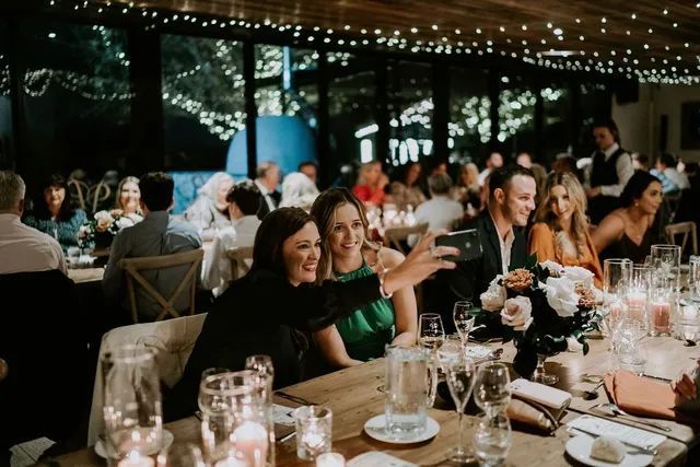 A group of people are sitting at a table taking a selfie.