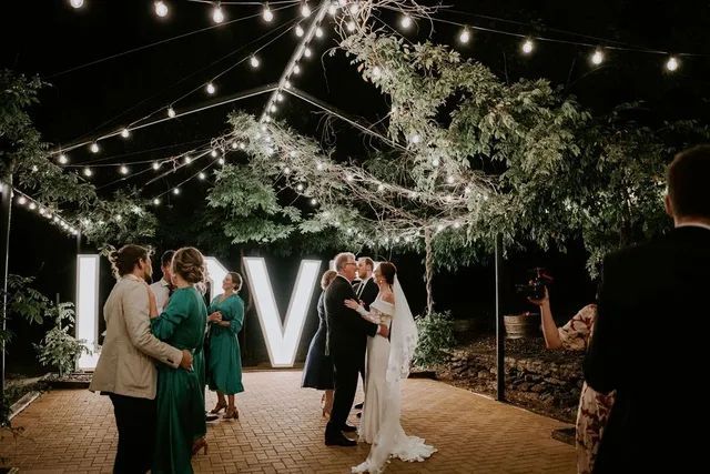 A bride and groom are kissing in front of a large love sign.