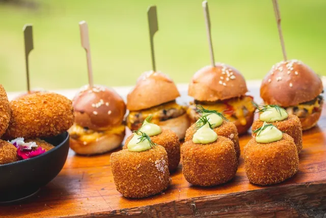 A wooden table topped with a variety of appetizers and burgers.