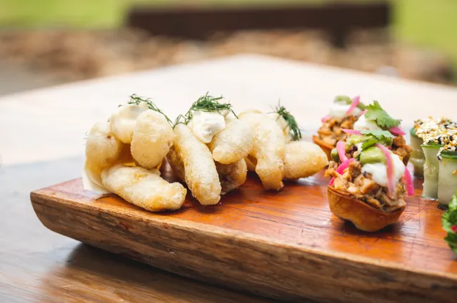 A wooden cutting board topped with a variety of food on a table.