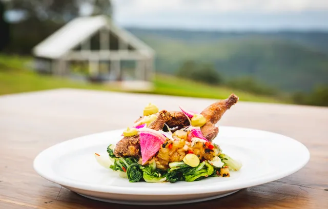 A plate of food on a wooden table with a house in the background.