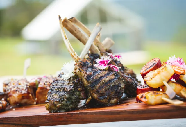 A wooden cutting board topped with meat and vegetables.