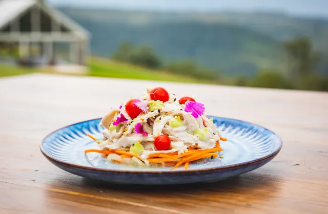 A blue plate topped with a salad on a wooden table.