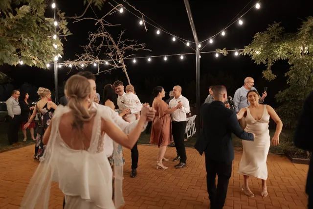 A group of people are dancing under a canopy at a wedding reception.