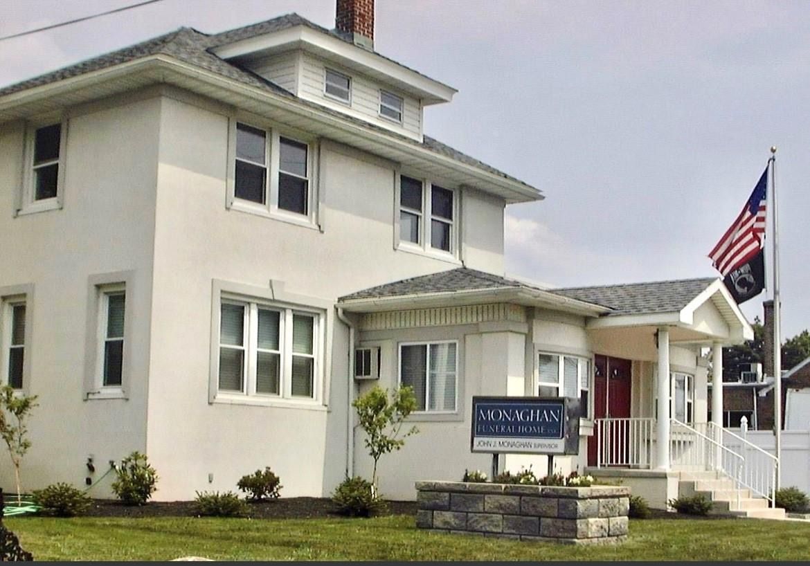 Two-story white building with an American flag and a sign reading 