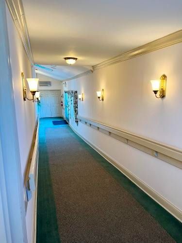 Long hallway with carpet, handrail, and wall sconce lighting.