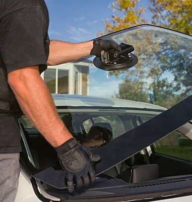 A man is installing a windshield on a car.