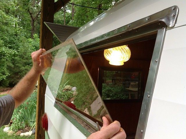 A person is holding a piece of glass in front of a window.