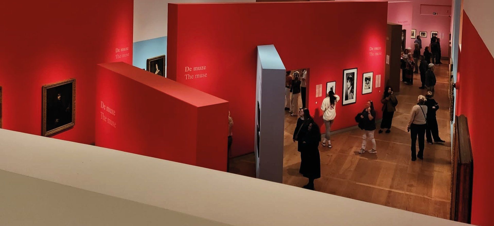A slight bird eye view of people walking through a museum in a red room