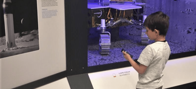 A child listening to the Podcatcher audio guide whilst looking at a space exhibit in a museum