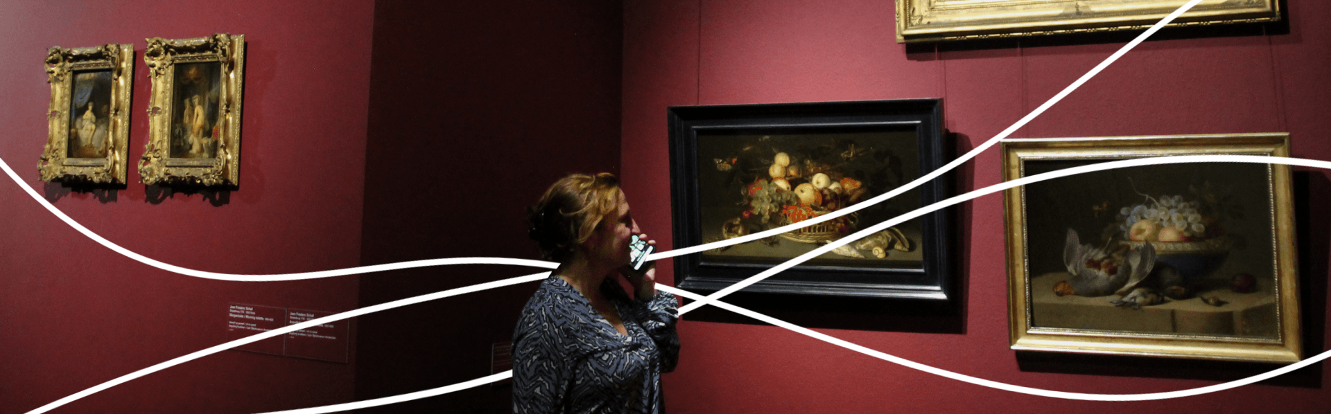 A woman listening to an audio guide in a museum with paintings on the wall and white lines flowing through the photo