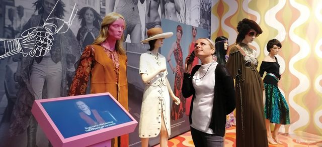 Marlise Meuter listening to a Podcatcher whilst looking at a museum display at an fashion exhibition