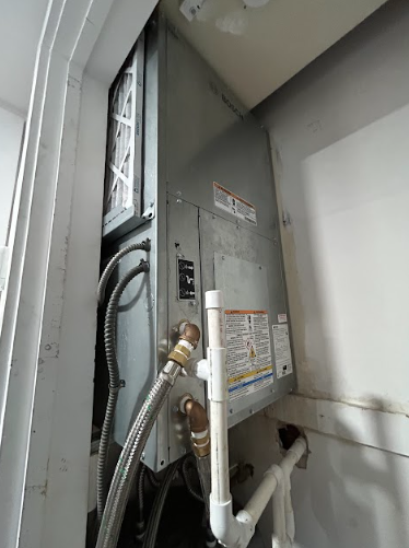 A metal HVAC unit is installed in a closet, with a filter, pipes, and electrical components visible.