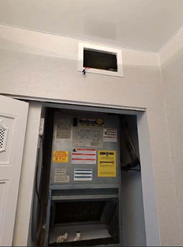HVAC unit in a closet. Vent opening in ceiling. White walls and door.