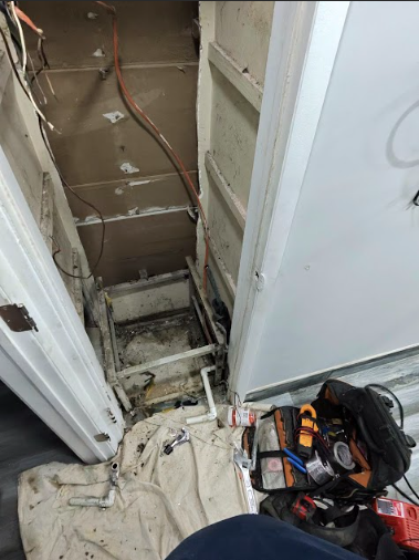 Open doorway reveals ceiling and metal structure, wires and tools visible.