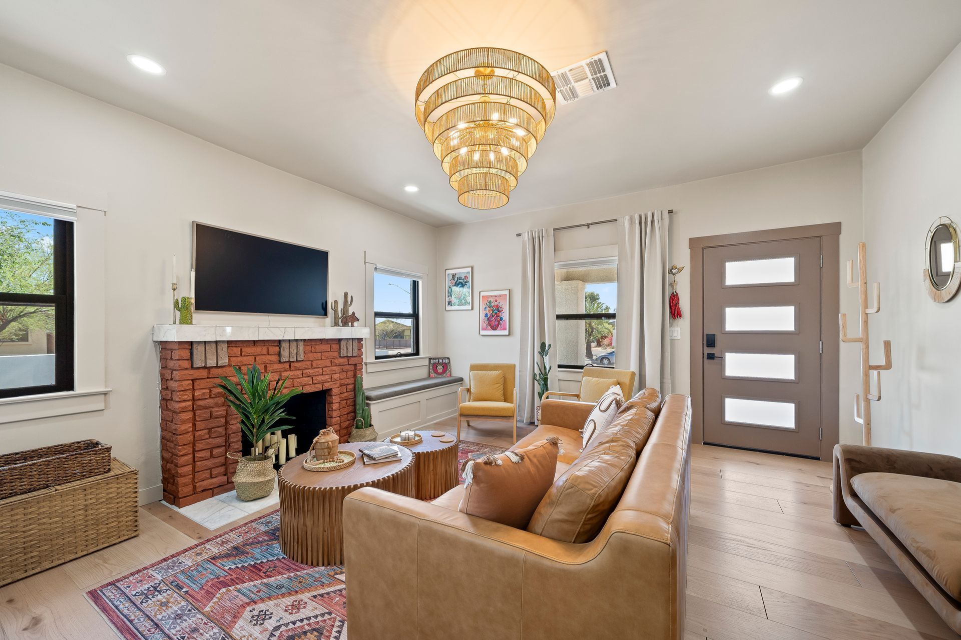 Living room with a brick fireplace, leather sofa, and ornate chandelier.