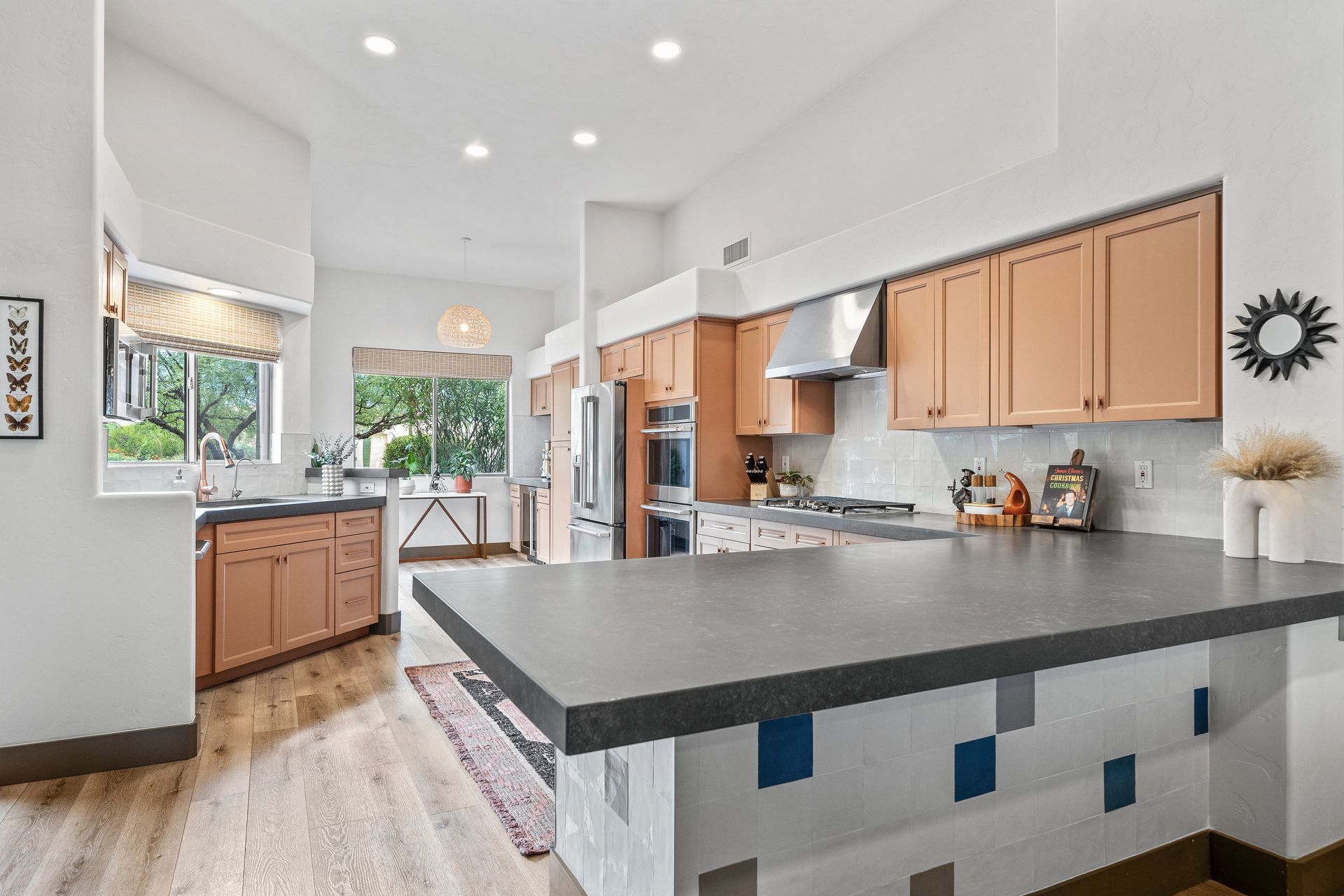 Spacious kitchen with light wood cabinets, dark island, and tall ceilings. Bright and airy.