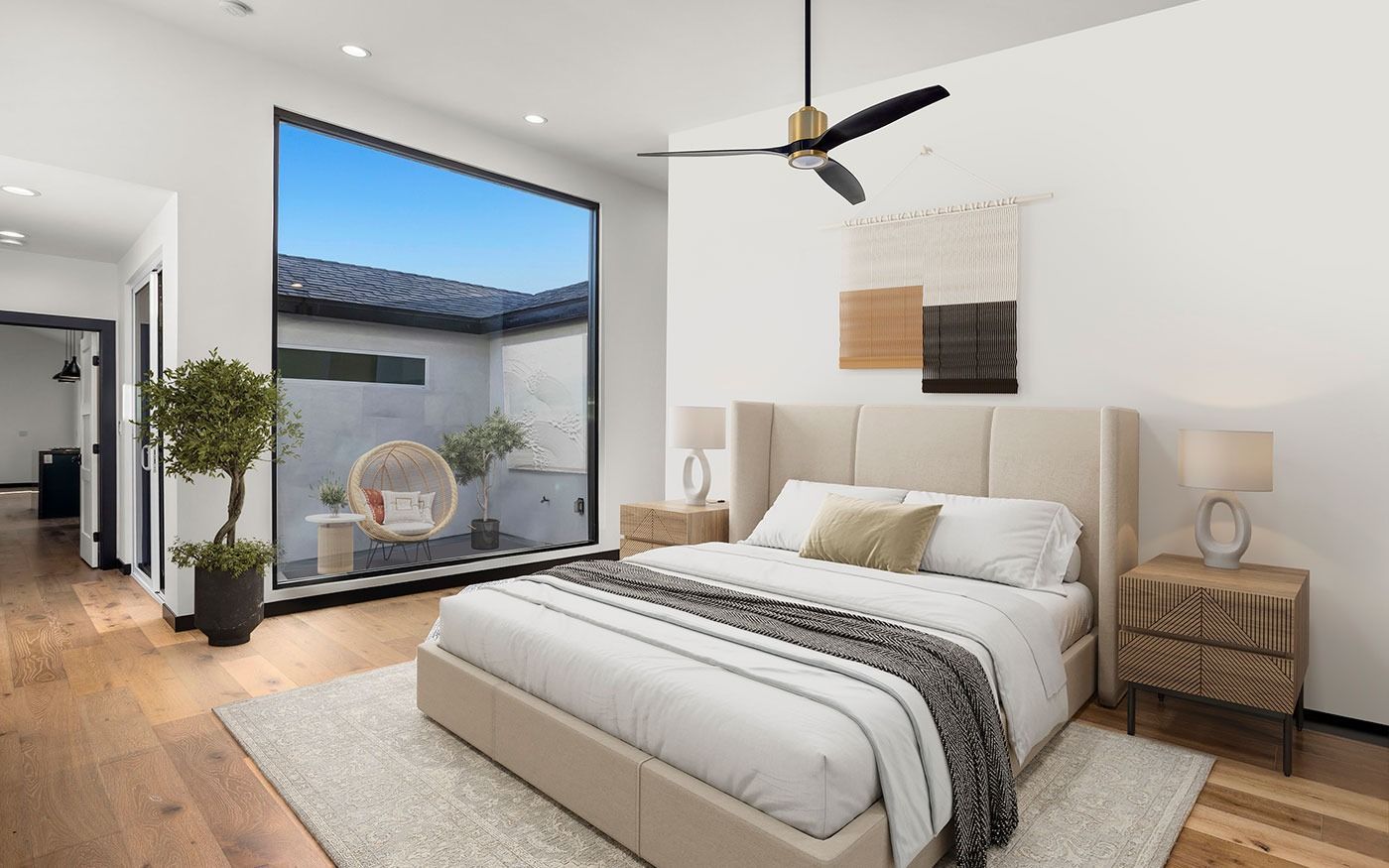 Bedroom with bed, nightstands, large window to patio, hardwood floor, ceiling fan.