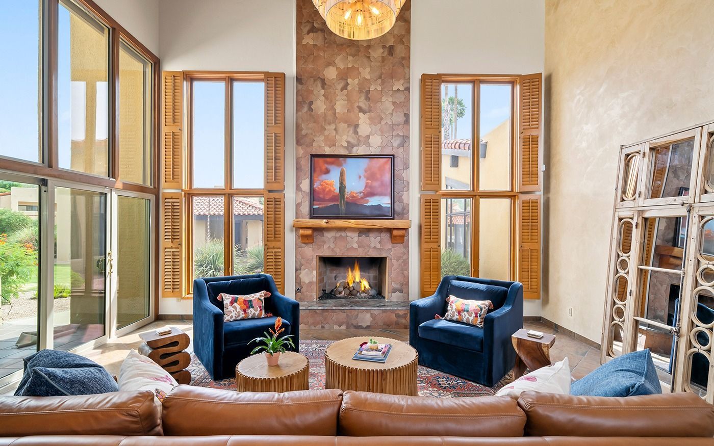 Kitchen with wooden cabinets, island with seating, pendant lights, and marble countertops.