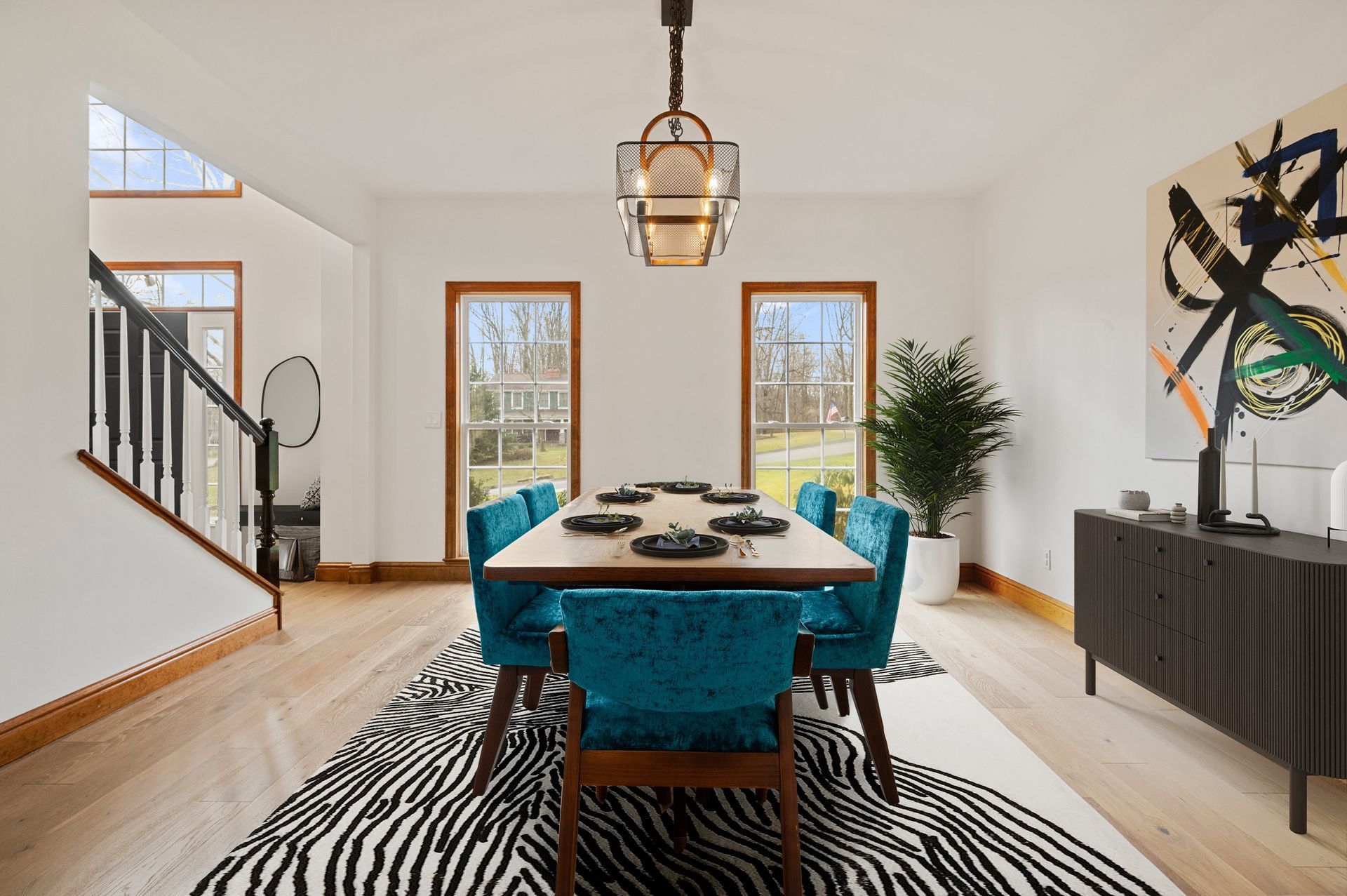 Dining room with teal chairs, zebra rug, and abstract art.