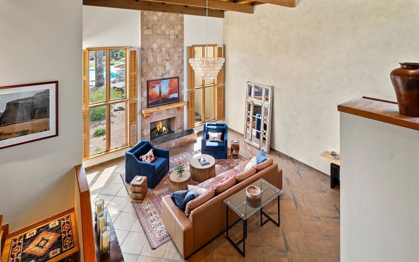 Living room with blue armchairs, leather sofa, fireplace, and large windows.