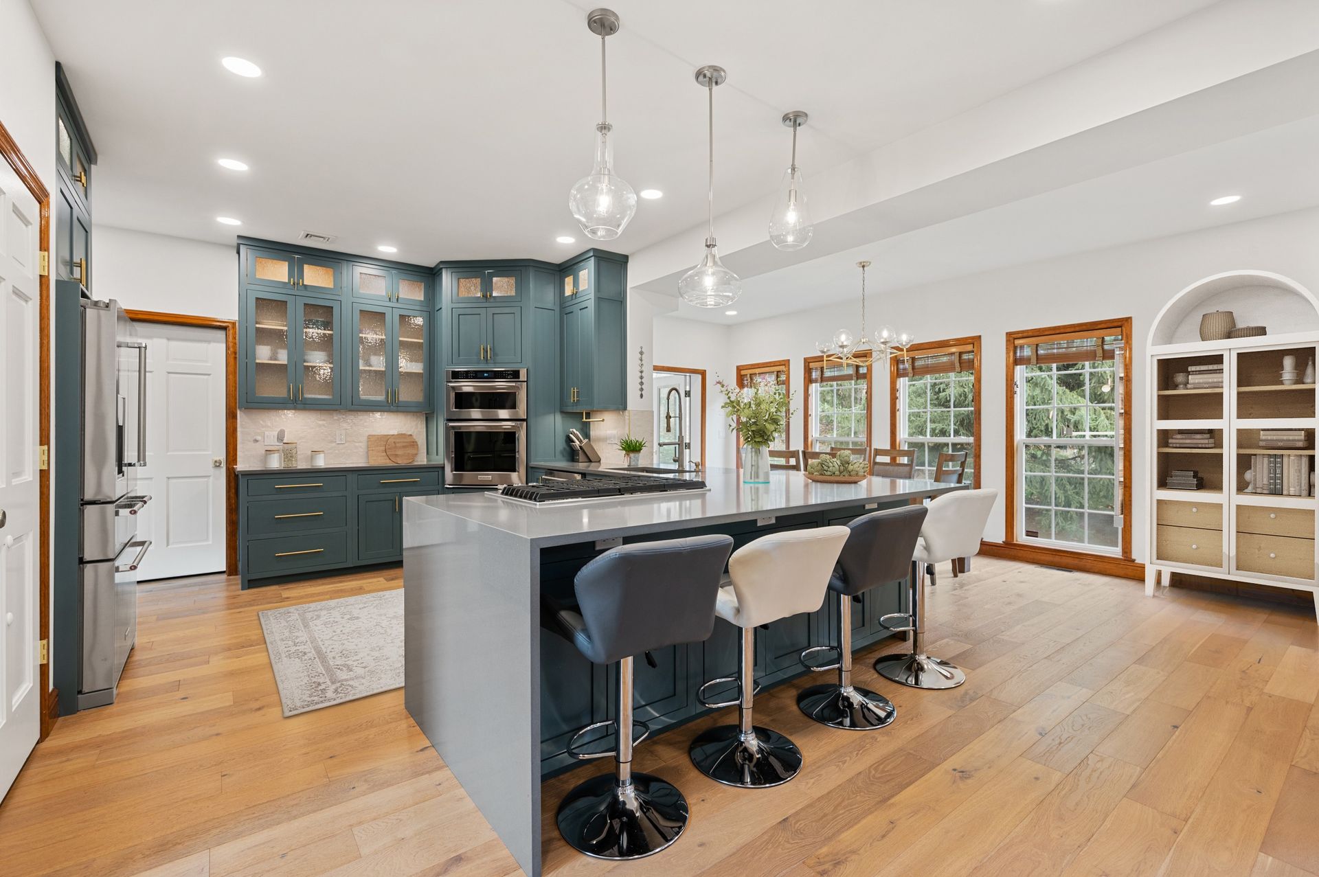 Modern kitchen with blue cabinets, island with stools, and hardwood floors.