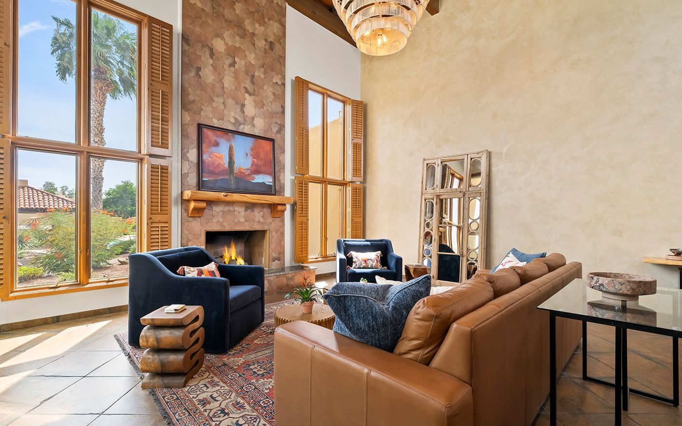 Living room with fireplace, large windows, leather furniture, and stone accent wall.