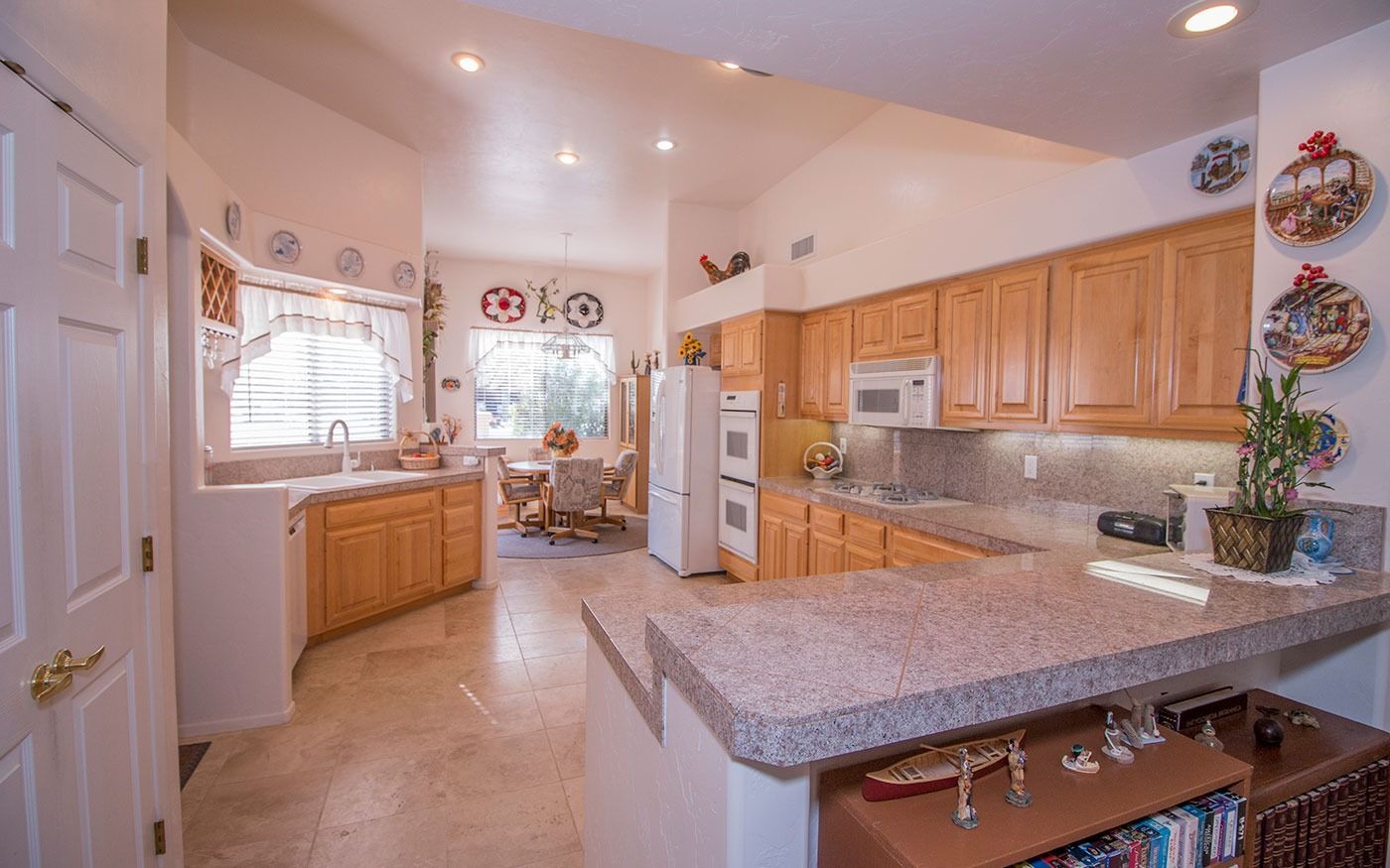 Kitchen with light wood cabinets, granite countertops, and a breakfast bar. Dining area visible in the background.