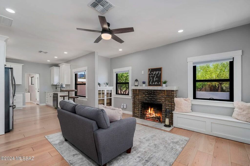Living room with gray walls, fireplace, gray couch, and wooden floor.