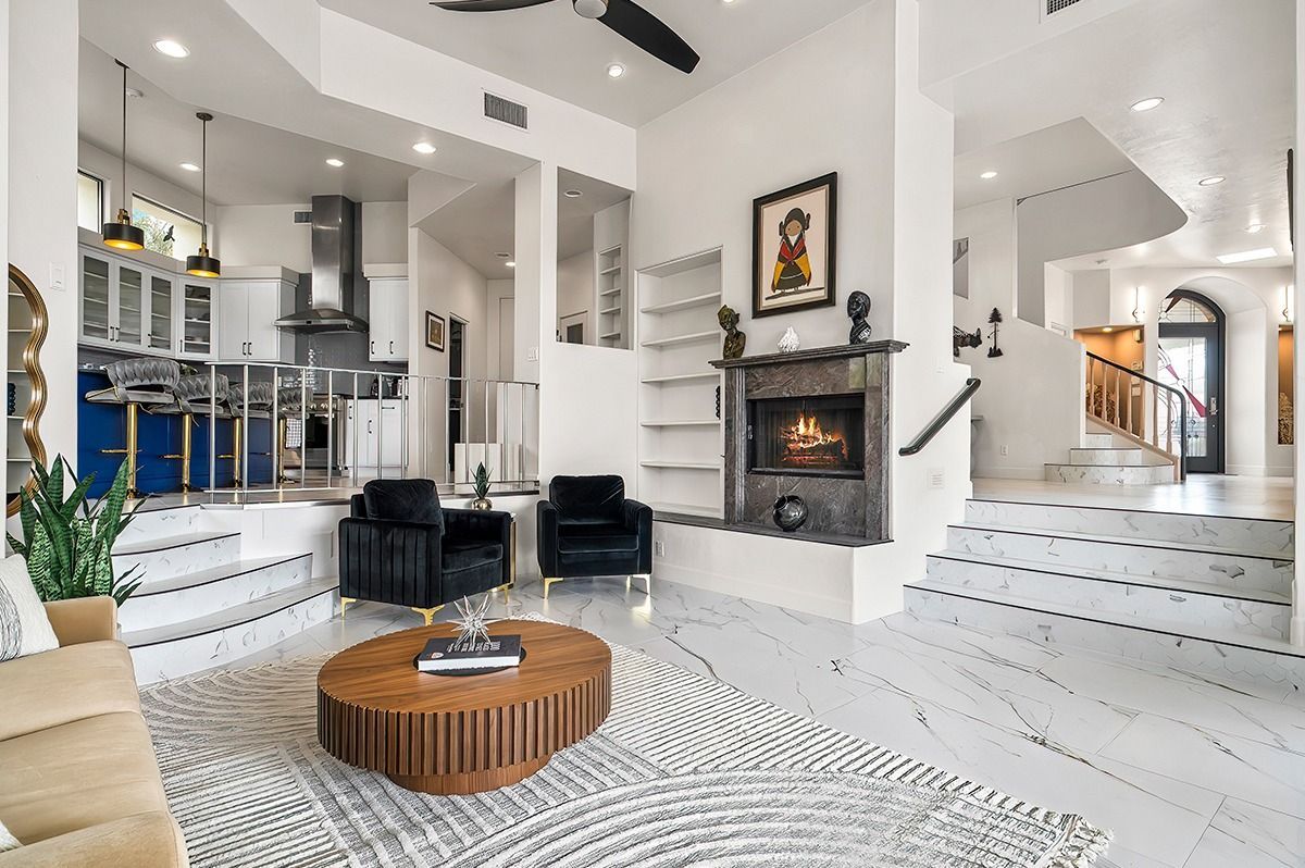 Spacious, modern interior with fireplace, open kitchen, and living room with blue accents, bright white walls, and marble stairs.