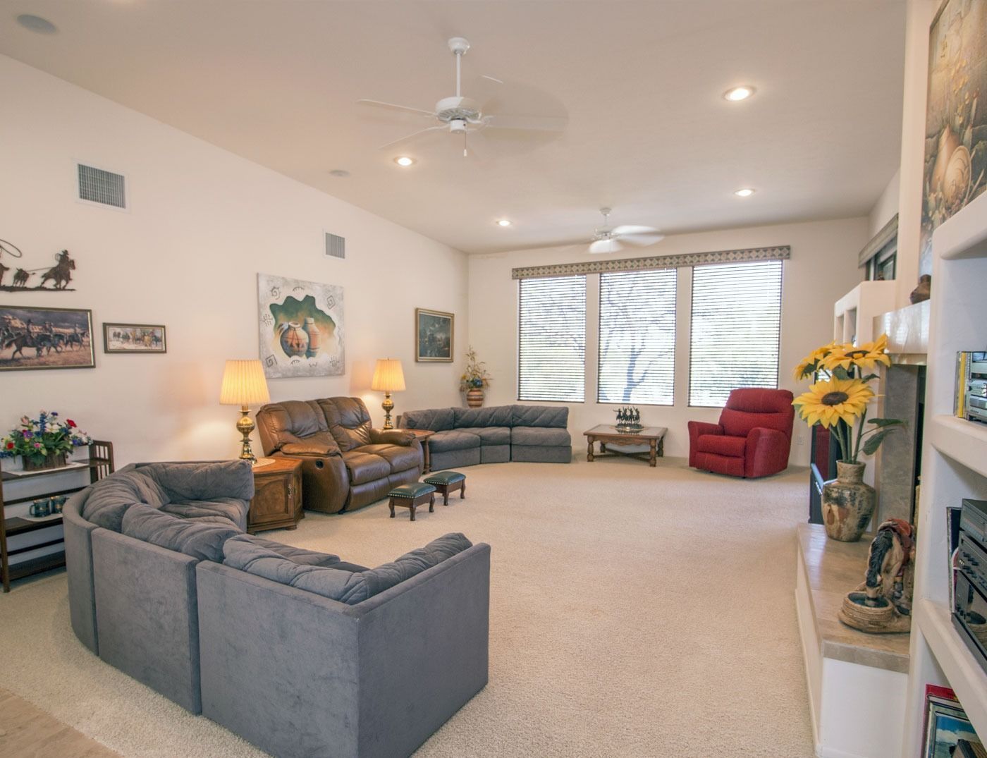 Spacious living room with a sectional sofa, recliner, and fireplace. Beige walls and carpet.