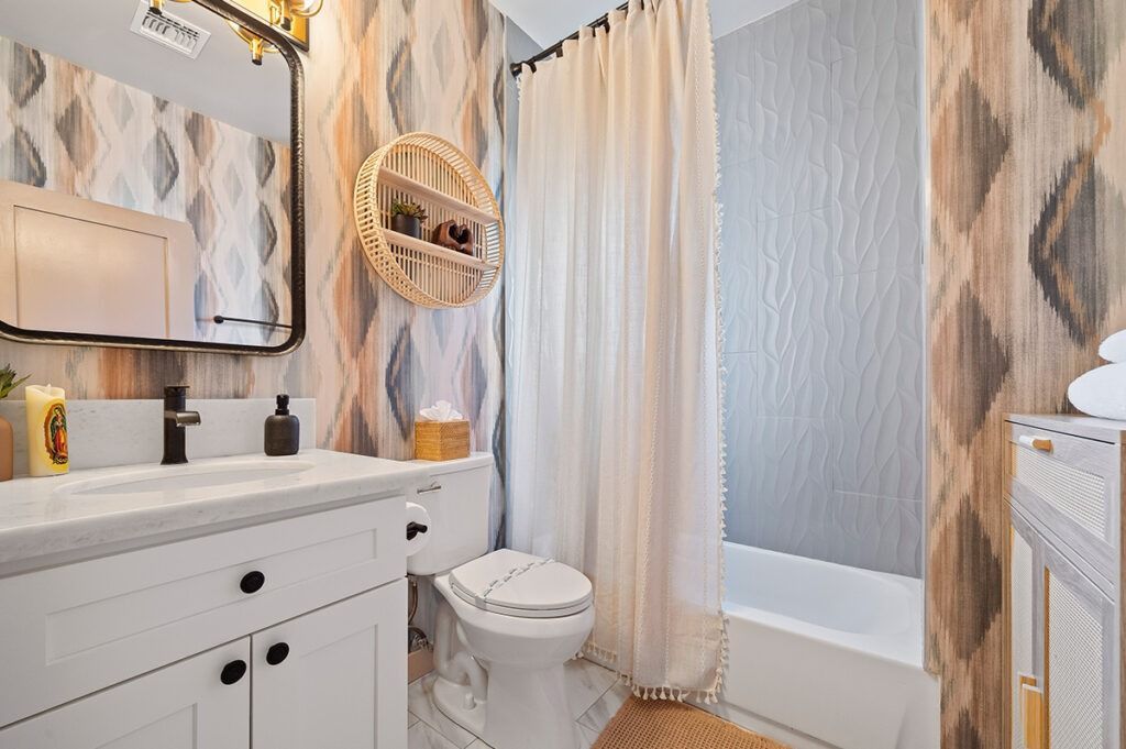 Bathroom with white vanity, patterned wallpaper, black mirror, and a white shower curtain.