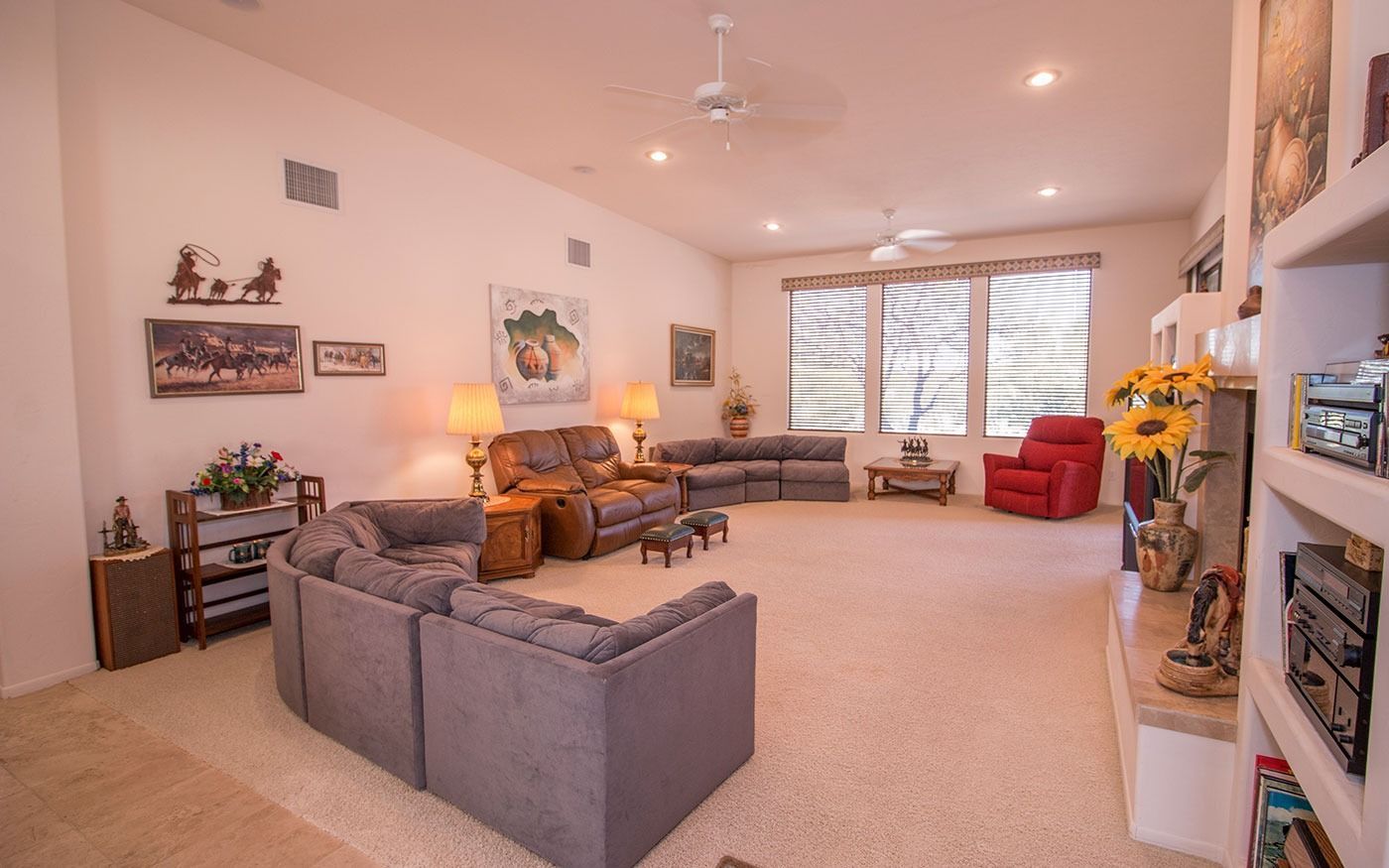 Spacious living room with neutral carpet, gray sofas, a red chair, and built-in shelves.