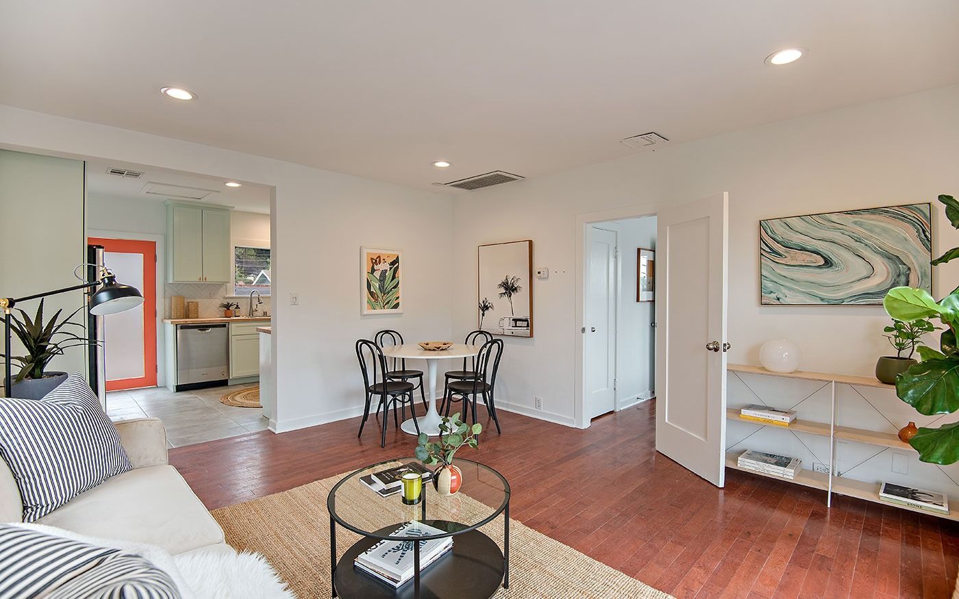 Living room with dining area, hardwood floors, white walls, and open doorway to kitchen.