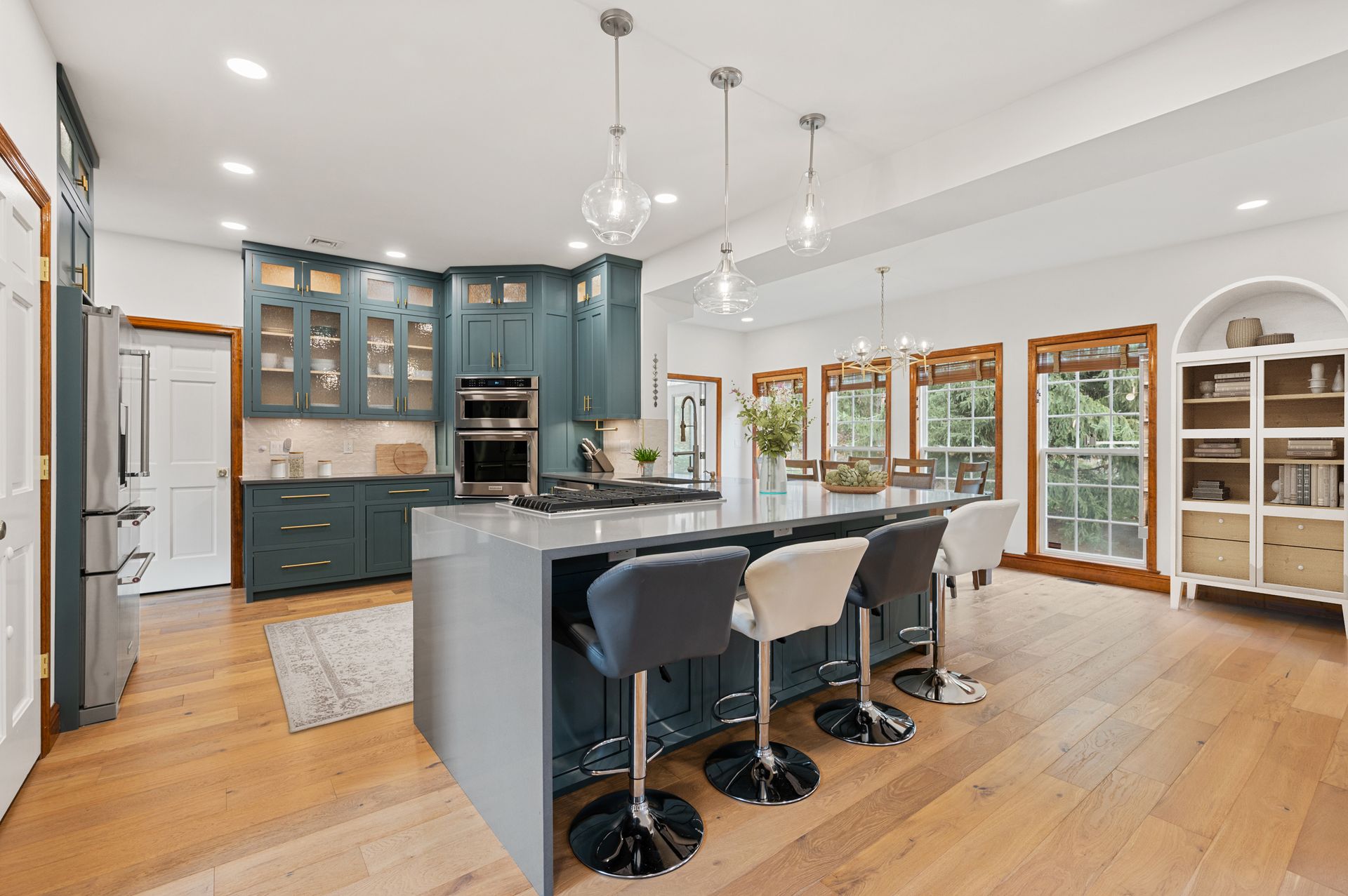 Spacious kitchen with blue cabinets, large island with bar stools, and light wood floors.