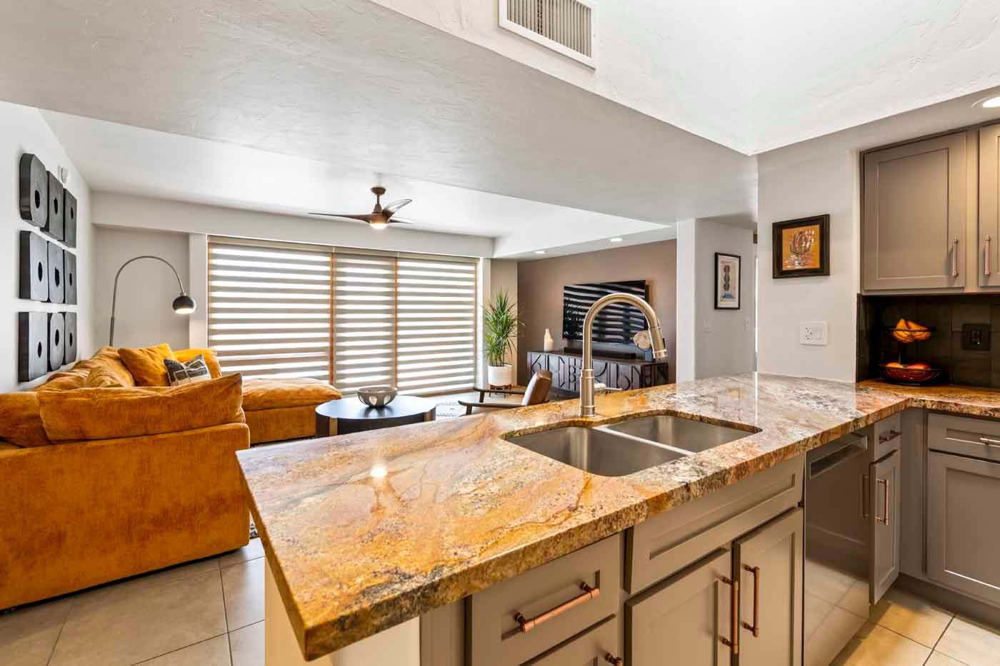 Open-concept kitchen and living area. Granite countertops, gray cabinets, and an orange couch.