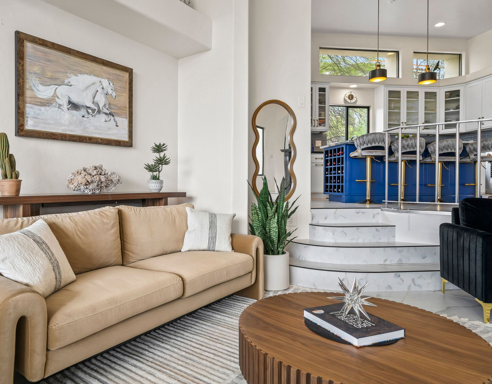 Living room with tan sofa, dark wood table, blue island, and white walls.