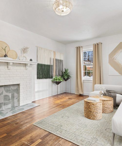 Cozy living room with a white fireplace, hardwood floors, and a neutral color scheme, with two wicker coffee tables.