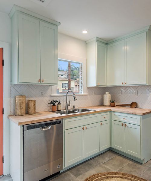 A light teal kitchen with wood countertops and stainless steel appliances.