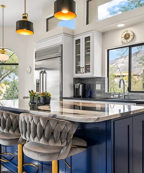 Stylish kitchen with blue island, stainless steel fridge, and mountain view.