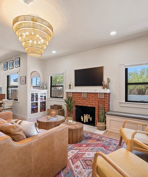 Living room with leather sofa, fireplace, wooden tables, and decorative rug.